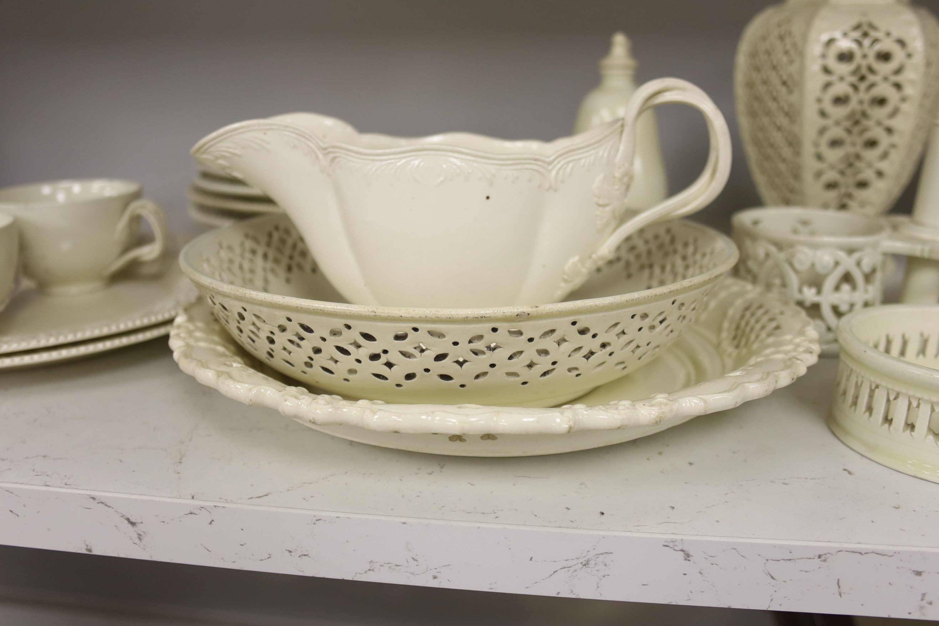 A collection of creamware, circa 1800, Staffordshire and Yorkshire comprising three pairs of plates, with moulded laurel swags, pair of small bottle coasters, sauceboat, saucer dish, two teacups, cruet stand, two pear sh